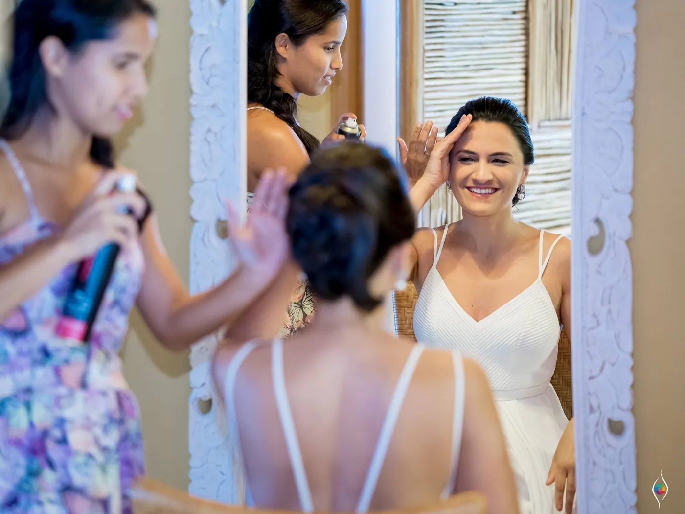Women gather close around Evy in her white dress, one in a floral top fixing her hair