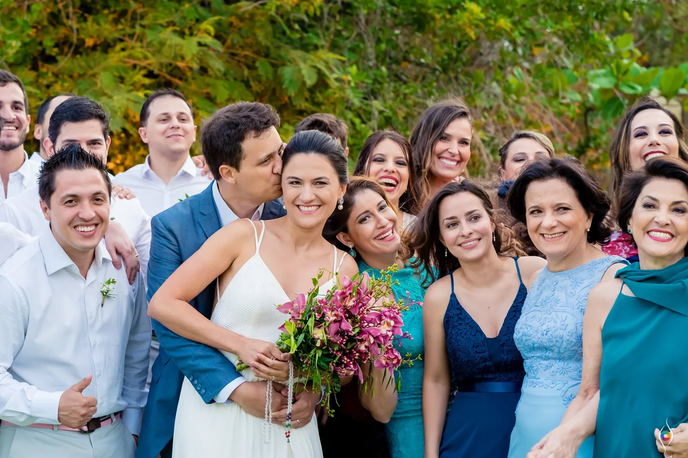 Evy holds her bouquet in a tightly packed group of laughing family and friends