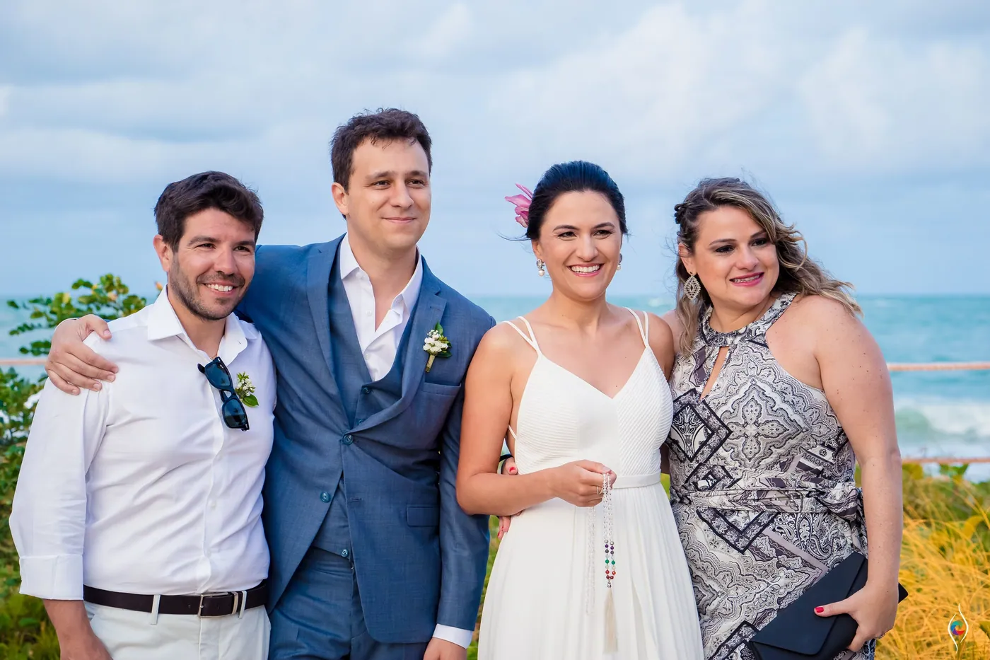 Thiago and Evy stand arm in arm with two friends, the sea at their backs