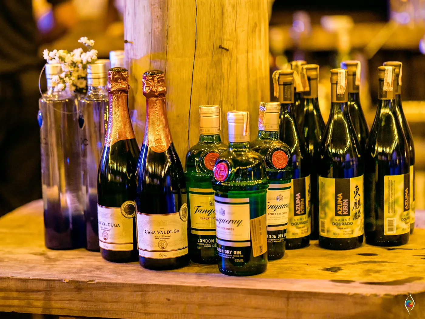 Bottles of sparkling wine, gin and wine line a rustic wooden bar