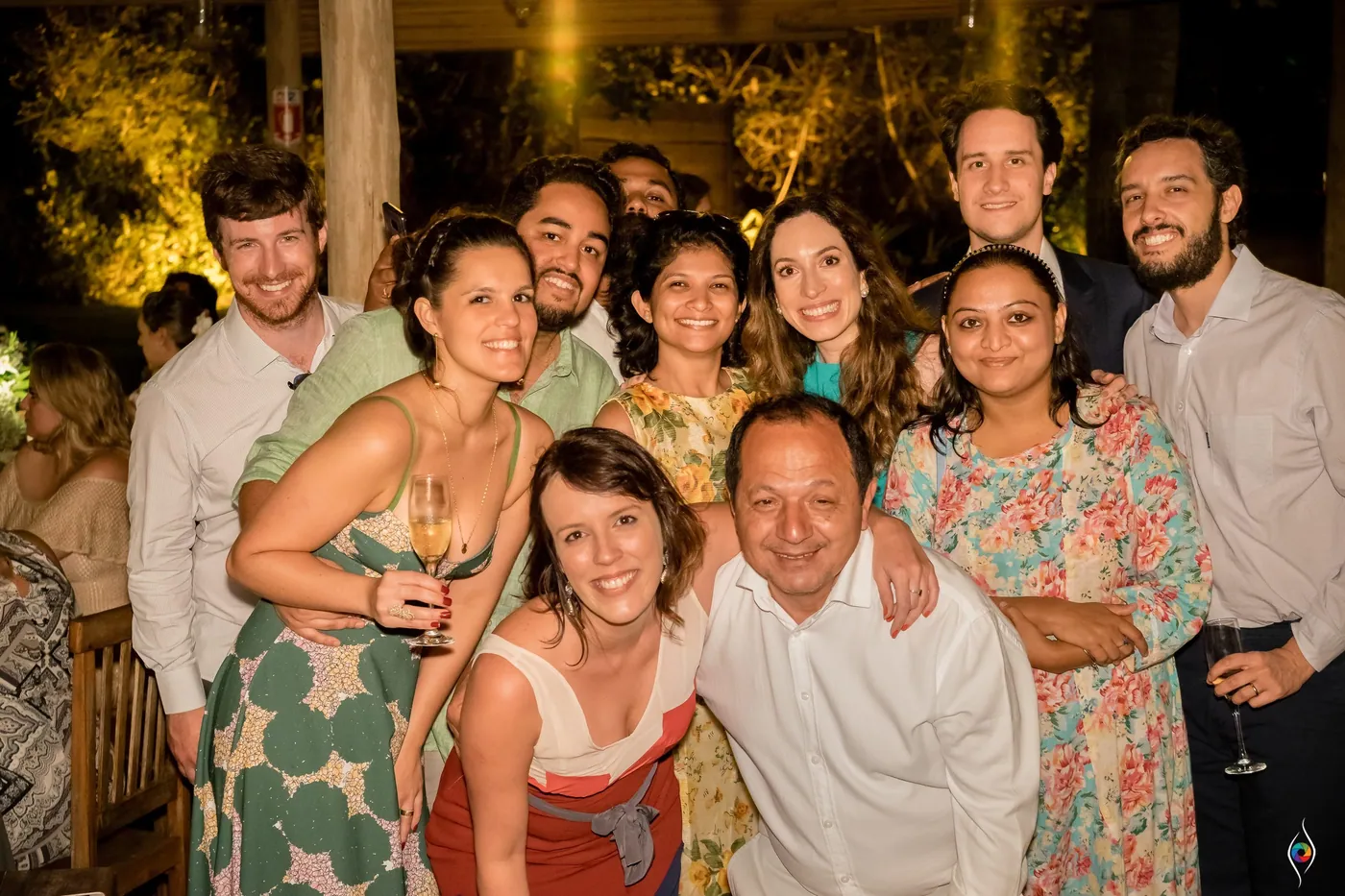 A tight knot of friends and family crowd in grinning, a man in white at the centre