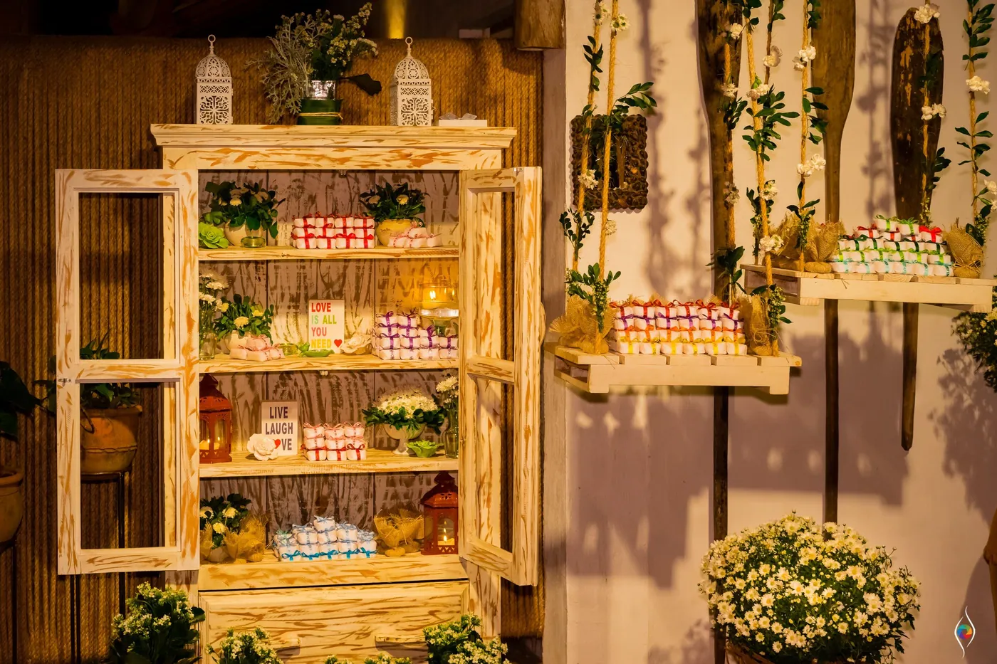 A rustic glass cabinet shelved with wedding favours and potted plants