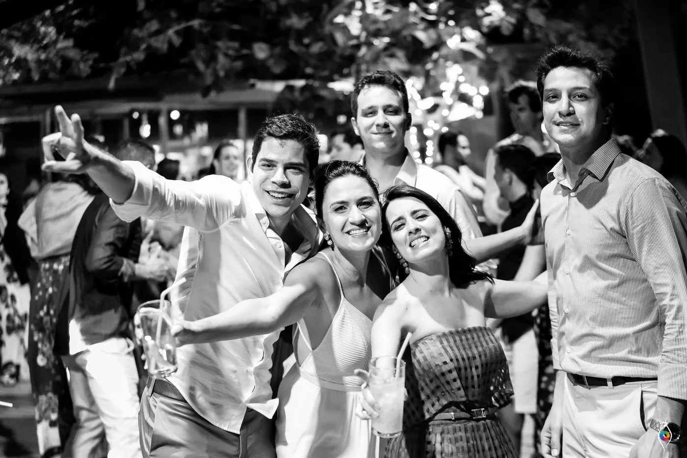 Friends pile together on the dance floor, pointing and grinning at the camera in black and white